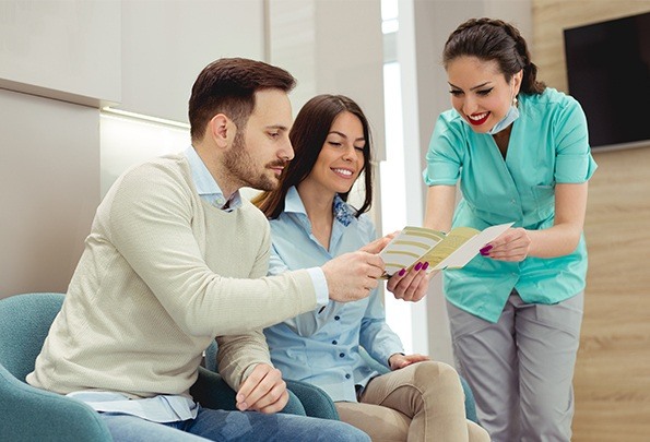Man and woman looking at brochure with dental team member