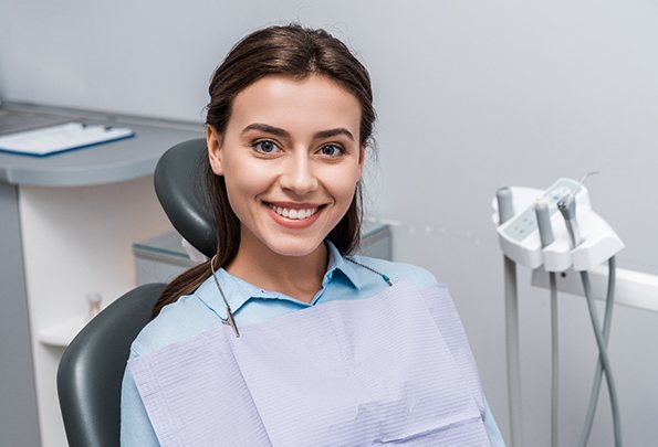 A young woman smiling and waiting to find out from her dentist if she is a candidate for Invisalign