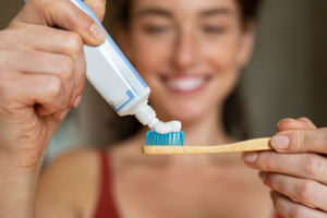 A woman squeezing toothpaste onto her toothbrush